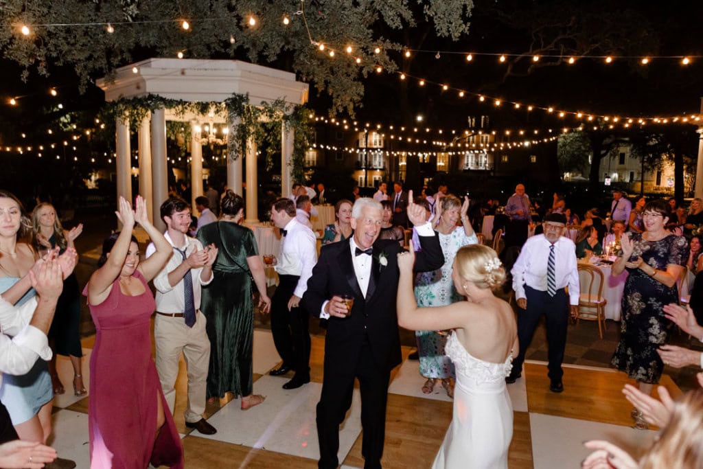Wedding reception dance floor with guests dancing under string lights.