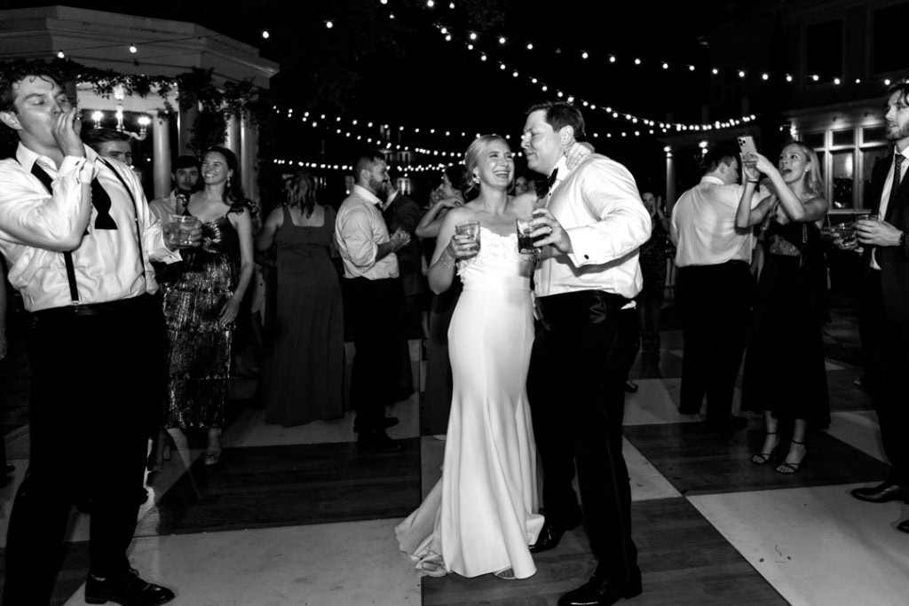 Bride and groom dancing at New Orleans wedding reception with guests and string lights.