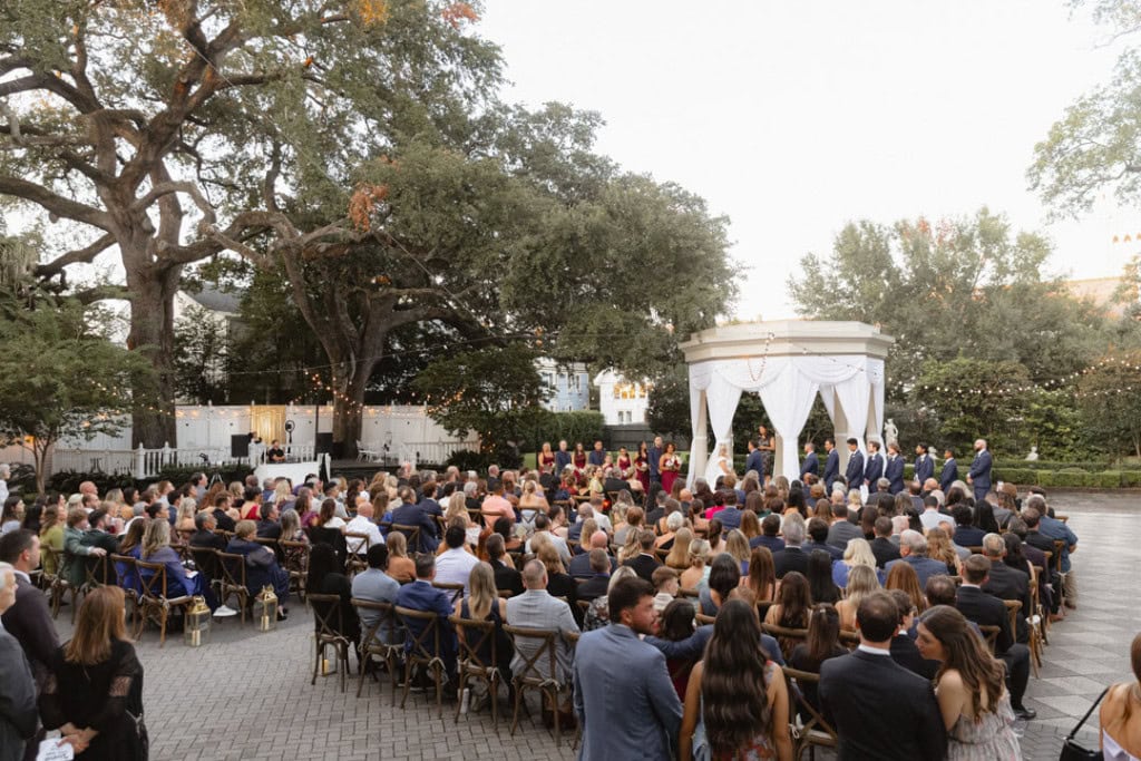 Wedding ceremony in New Orleans with guests and officiant under a white canopy.