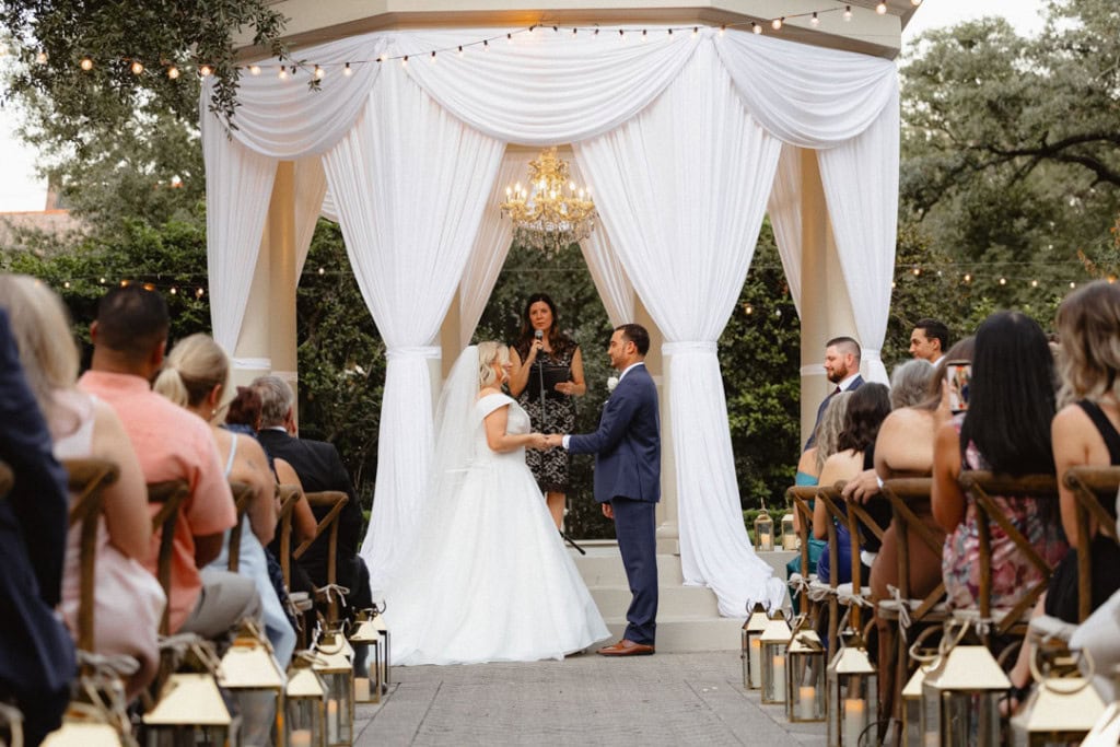 Wedding ceremony in New Orleans with bride and groom exchanging vows under a canopy.