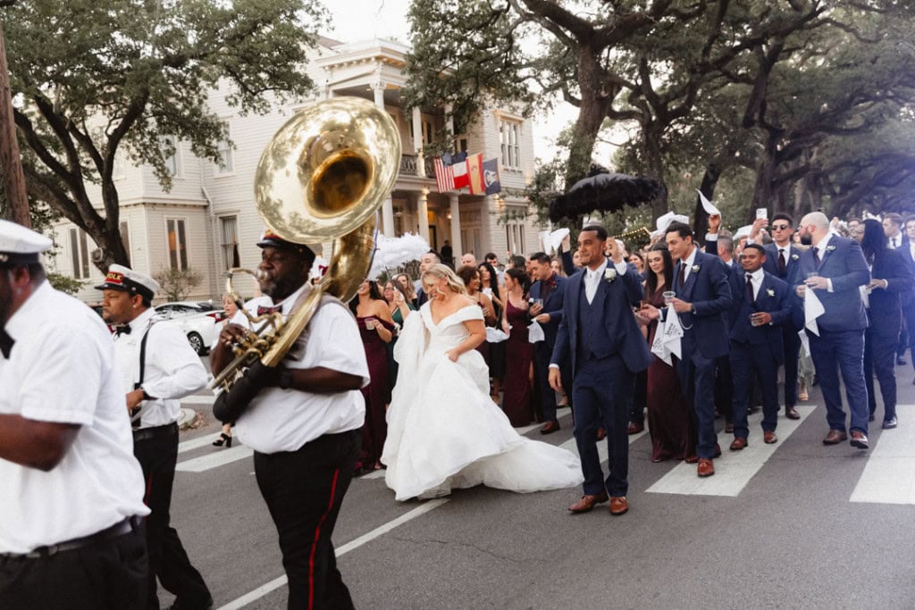 Wedding parade in New Orleans with band and bride in white dress.