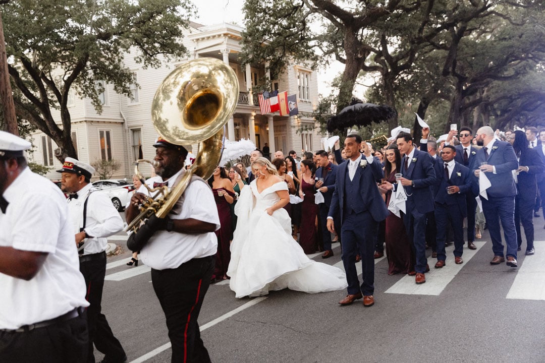 Wedding parade in New Orleans with band and bride in white dress.