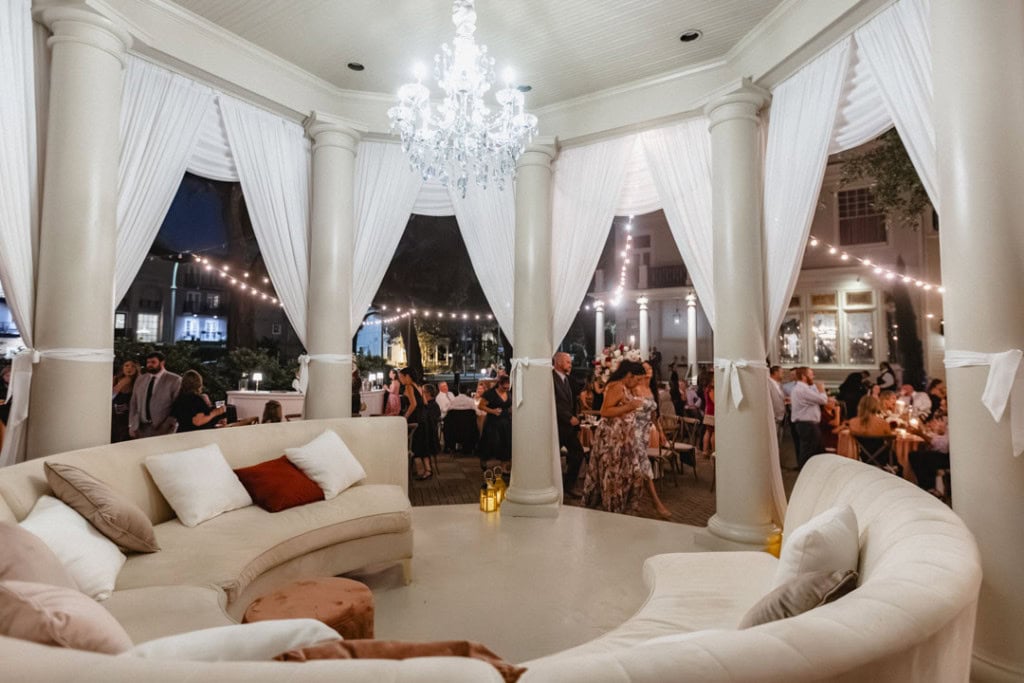 Elegant wedding reception in New Orleans with white drapes and chandelier lighting.