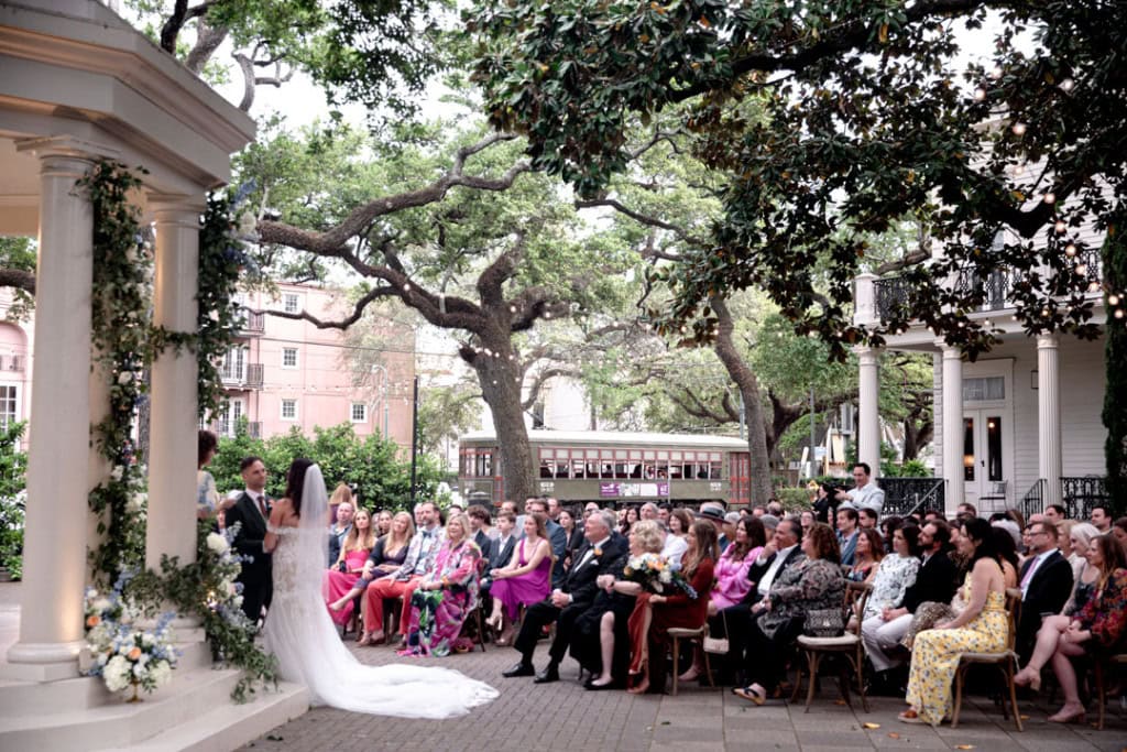 Wedding ceremony in New Orleans with guests and scenic trees.
