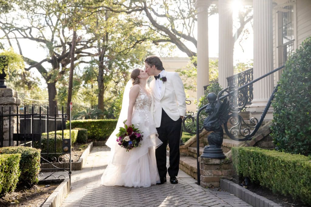 Bride and groom sharing a kiss outside a historic New Orleans house.