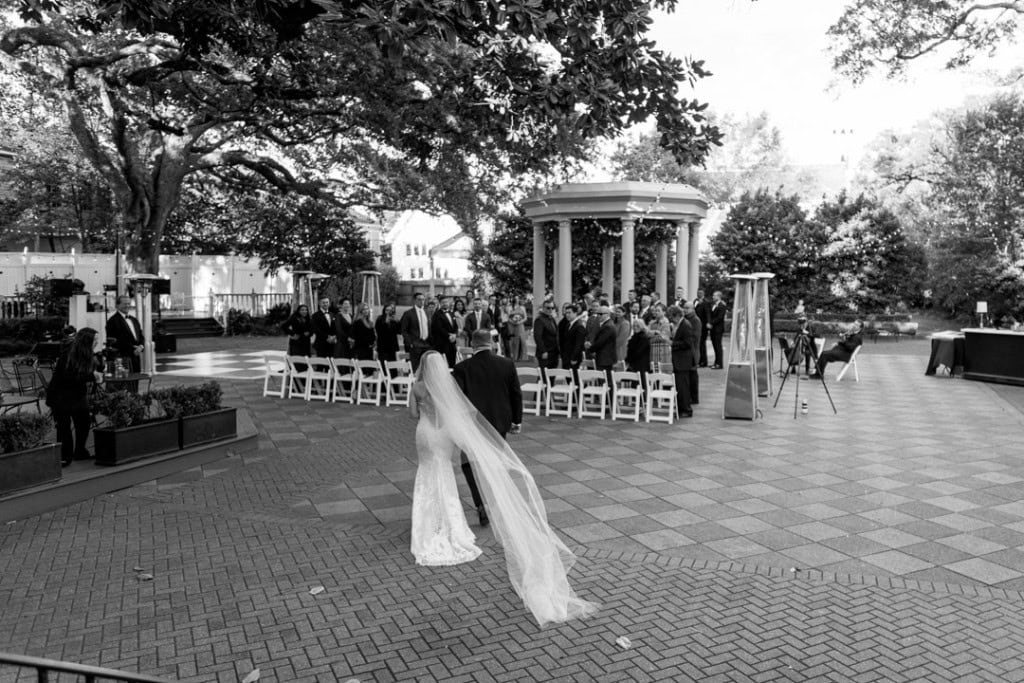 Bride and groom walking towards wedding ceremony in New Orleans park.