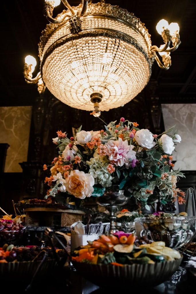 Elegant wedding reception table with floral centerpiece and chandelier lighting.