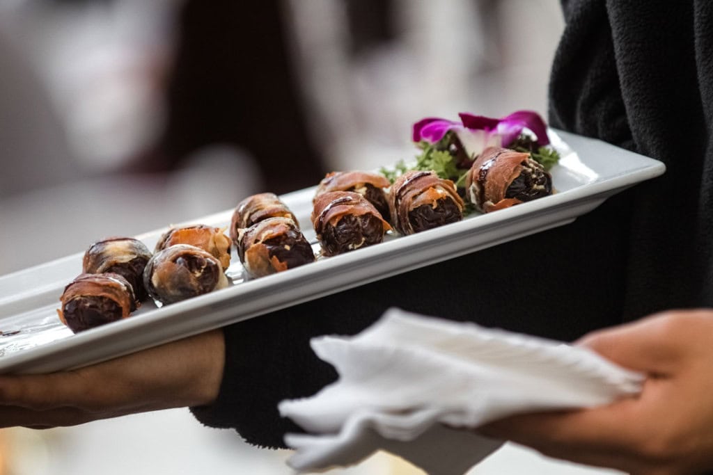 Close-up of a tray with chocolate desserts and purple flowers at a wedding.