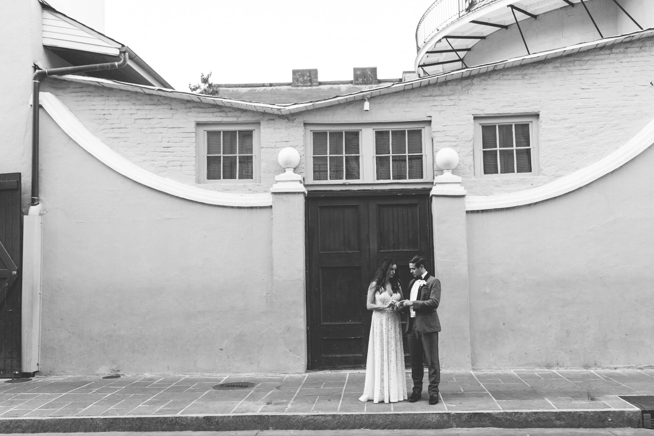 Bride and groom stand outside Latrobe's on Royal looking down at their wedding rings.