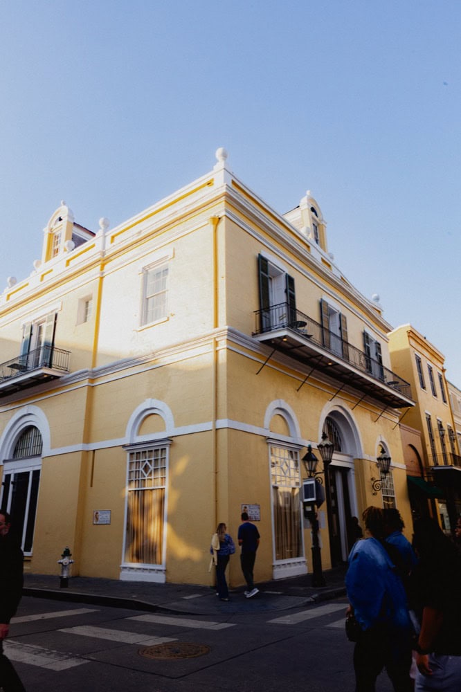 Historic yellow building in New Orleans with people on the street.