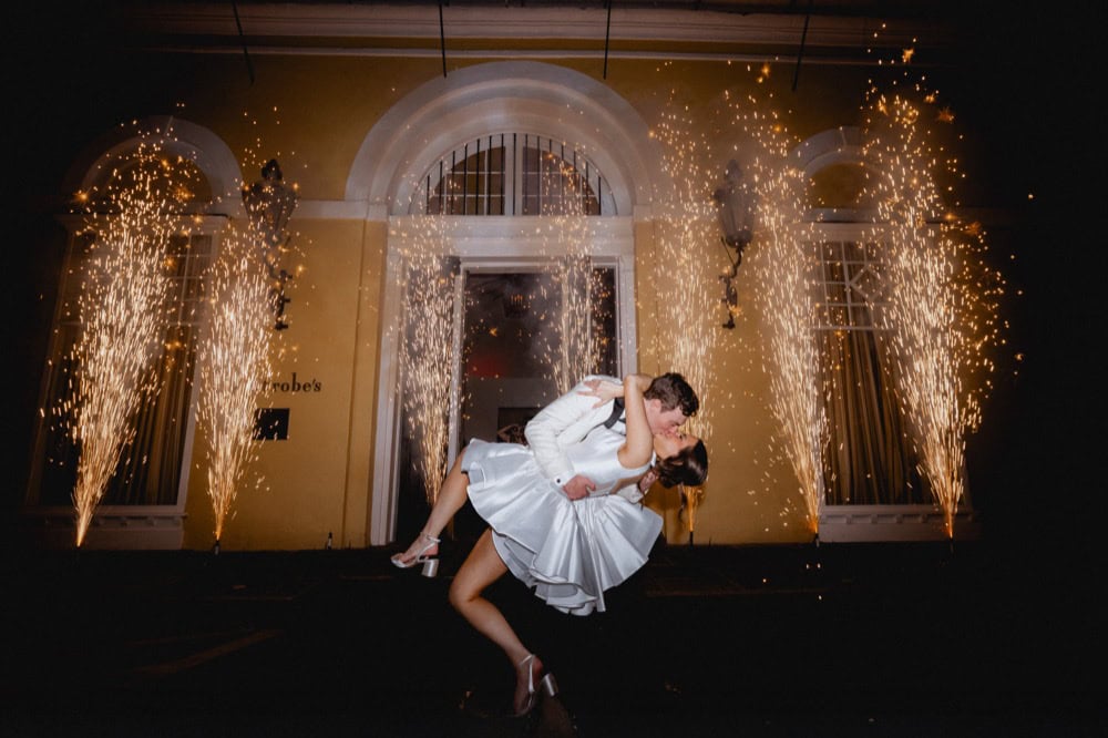 Bride and groom dancing with fireworks at wedding reception.