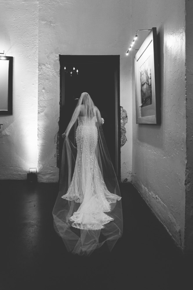 Bride in wedding dress walking through art gallery at night.