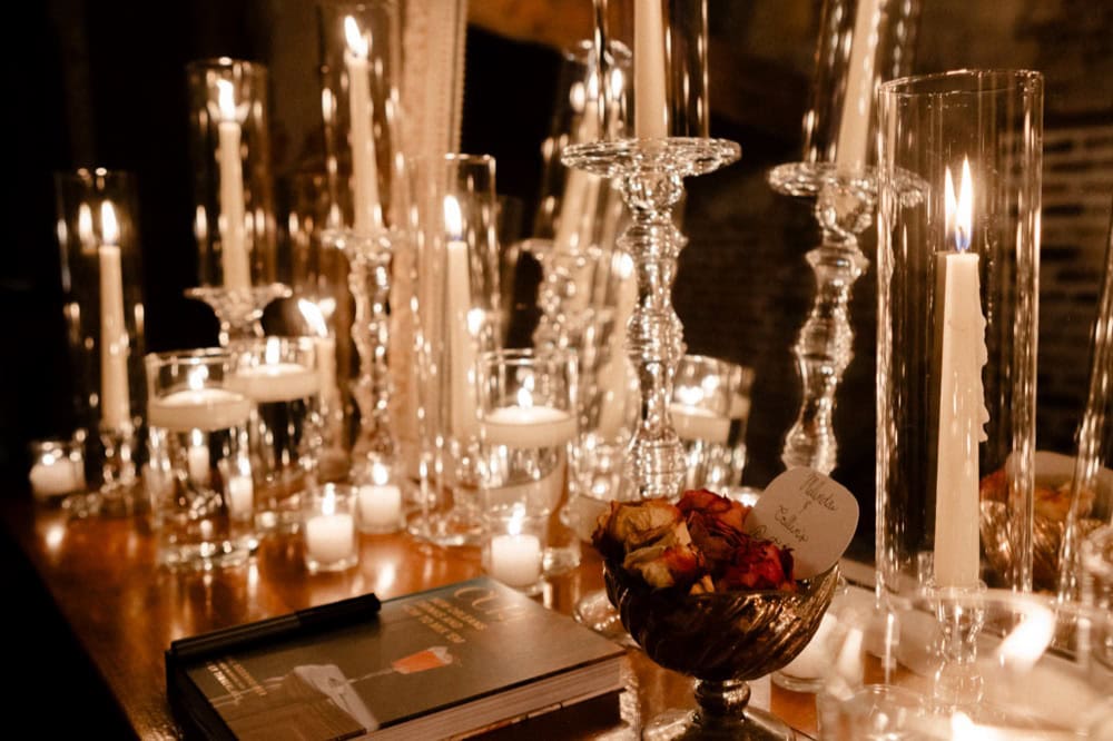 Wedding reception table with candles and floral centerpiece in warm lighting.