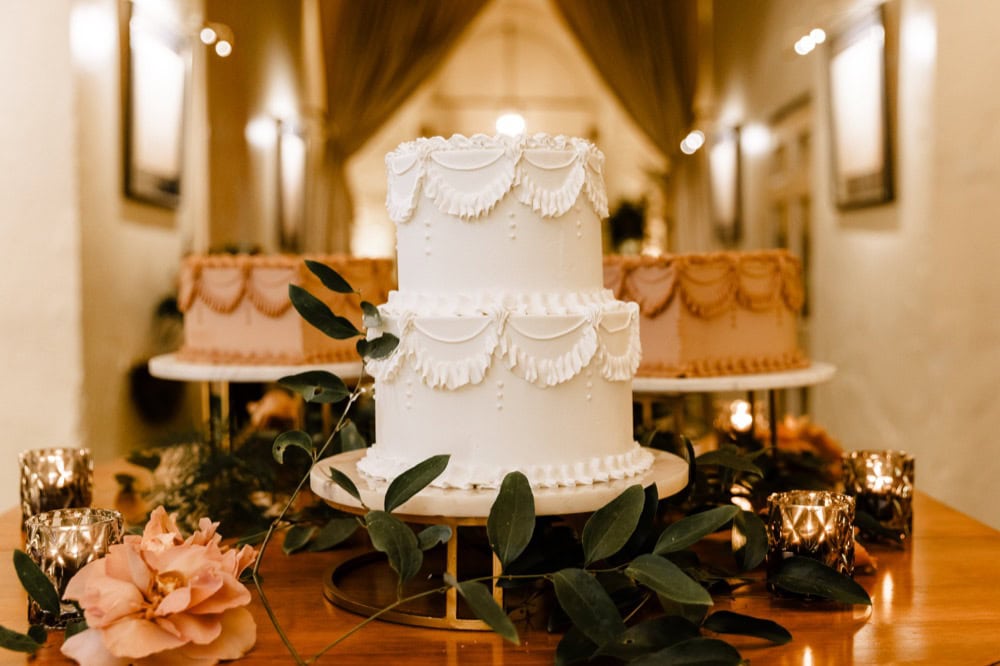 Beautiful white wedding cake with floral decorations and greenery.