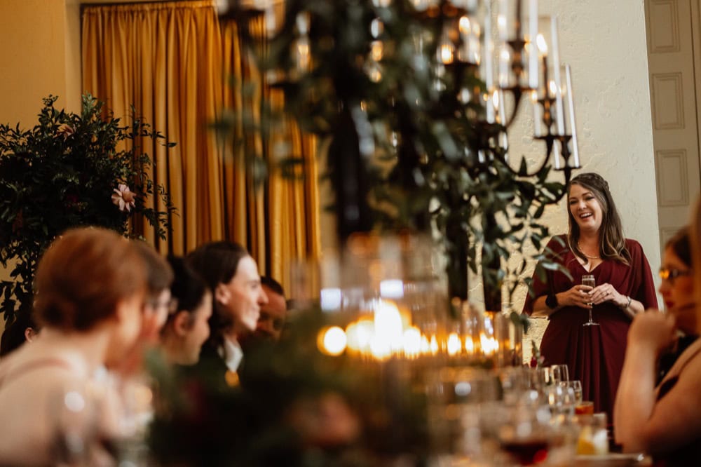 Wedding reception in New Orleans with guests and a speaker in elegant setting.