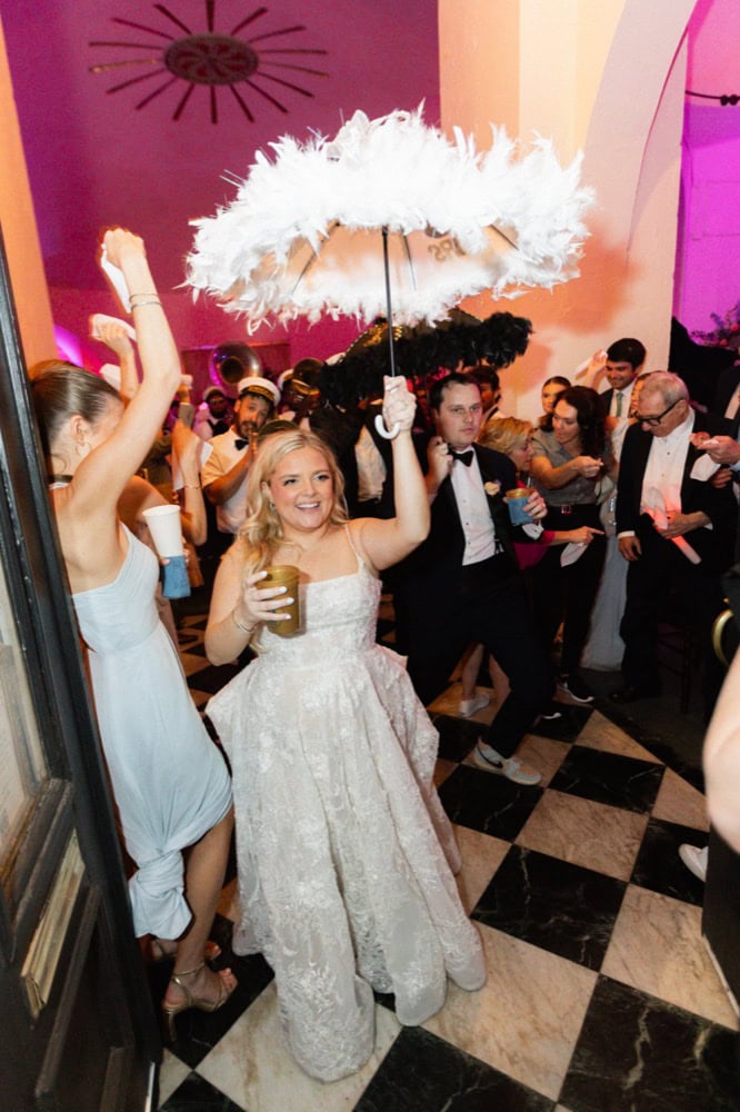 Bride with feathered parasol at wedding reception in New Orleans.