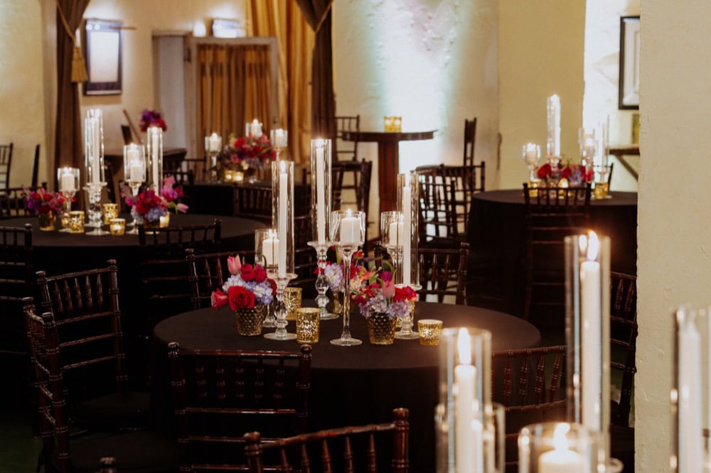 Glowing candles and red flowers adorn tables at a wedding reception at Latrobe's on Royal in New Orleans.