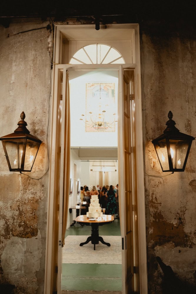 Wedding cake peaks through French doors which are flanked by gas lanterns at Latrobe's on Royal in New Orleans.