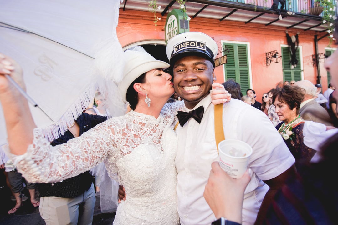 Bride gives a band member a kiss on the cheek on the street of New Orleans during a second line parade.