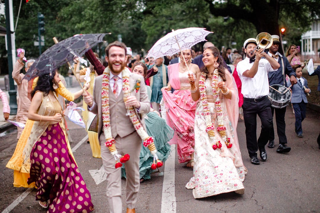 Vibrant New Orleans Indian wedding parade with musicians in colorful attire.