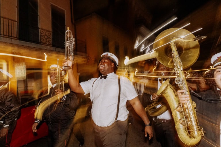 Brass band performing during a wedding second line at night in New Orleans with lively motion blur.