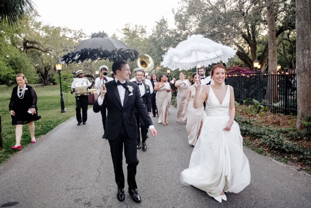 Bride and groom walking with wedding party and musicians at the Audubon Tea Room.