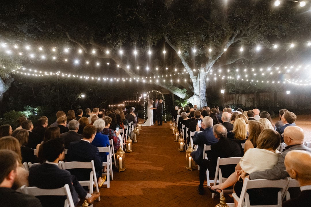 Outdoor wedding ceremony at night with string lights and large tree in New Orleans.