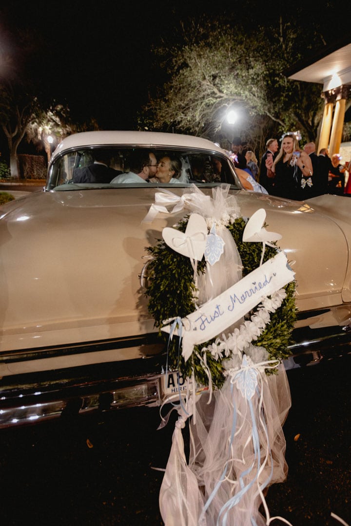 Vintage wedding car decorated with white flowers and hearts in New Orleans at night.