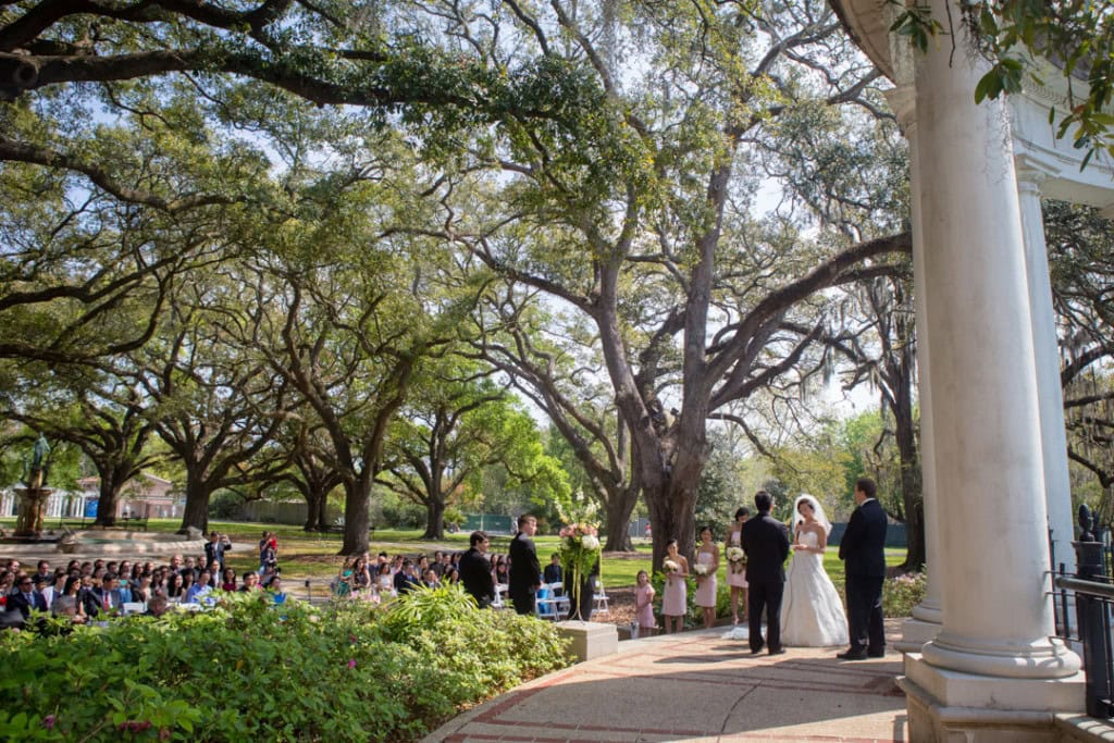 Wedding ceremony in a lush park with trees and guests in New Orleans at the Audubon Zoo.