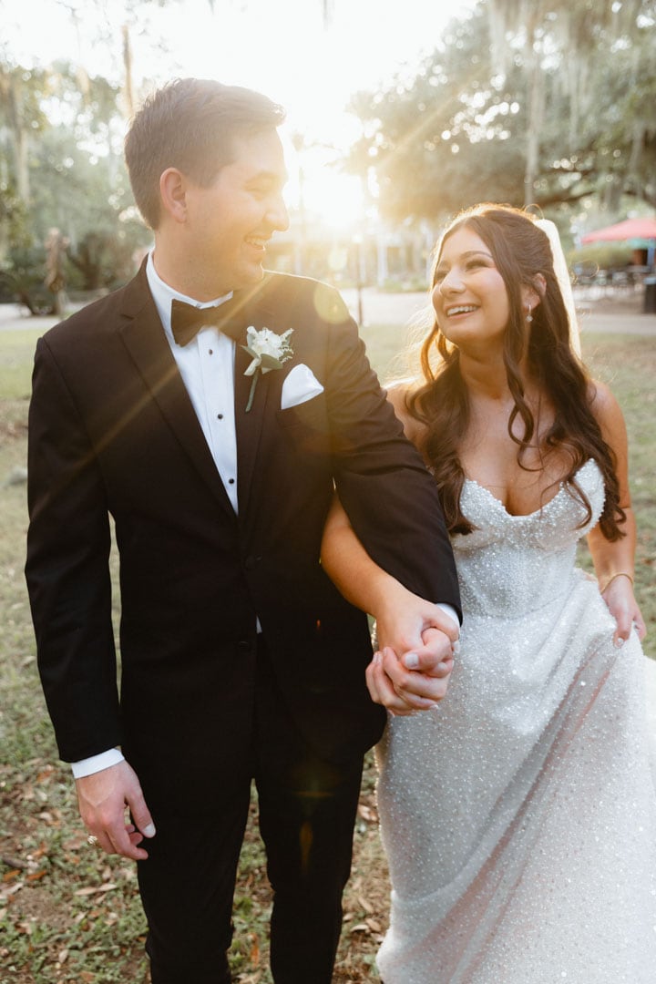 Happy bride and groom walking outdoors at sunset, wedding photography.