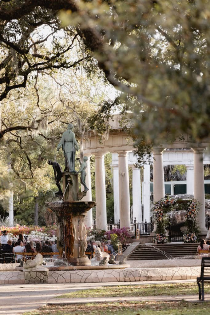 Wedding scene in New Orleans with fountain and classical columns.
