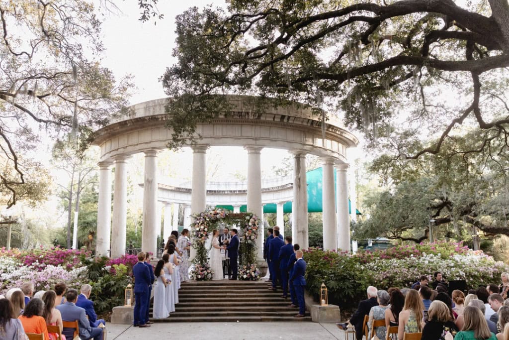 Wedding ceremony at the Sea Lion Colonnade at the Audubon Zoo in New Orleans with floral arch and guests.