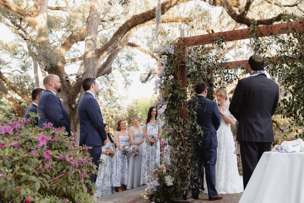 New Orleans wedding ceremony with bride, groom, and wedding party outdoors.