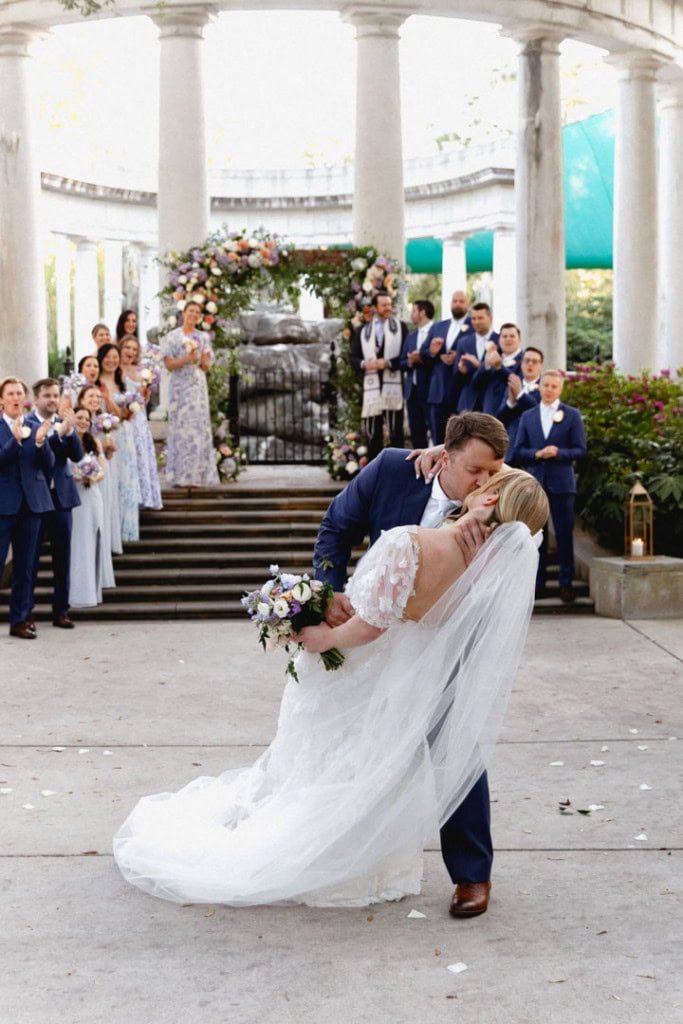 Bride and groom sharing a kiss at New Orleans wedding venue with guests.