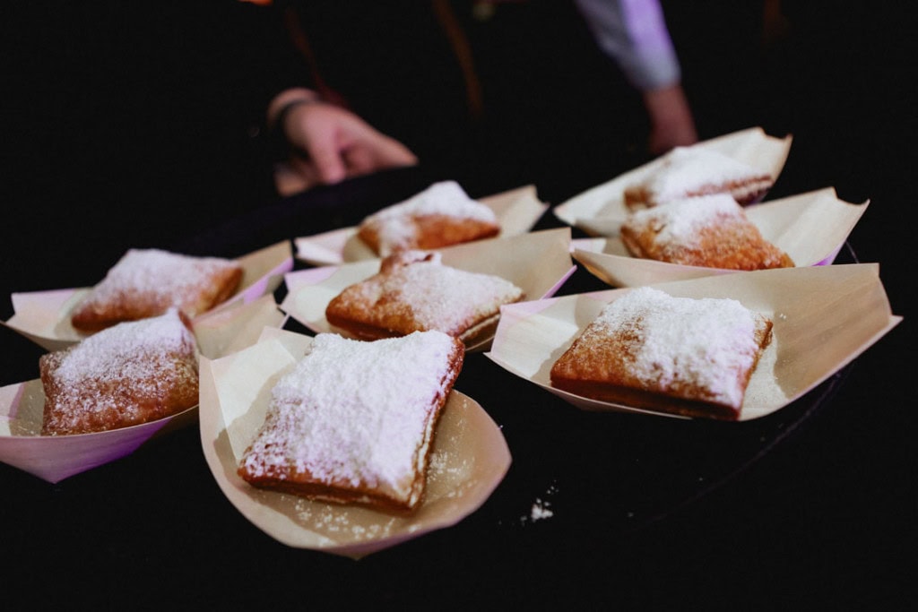 New Orleans beignets dusted with powdered sugar on serving plates at a wedding.