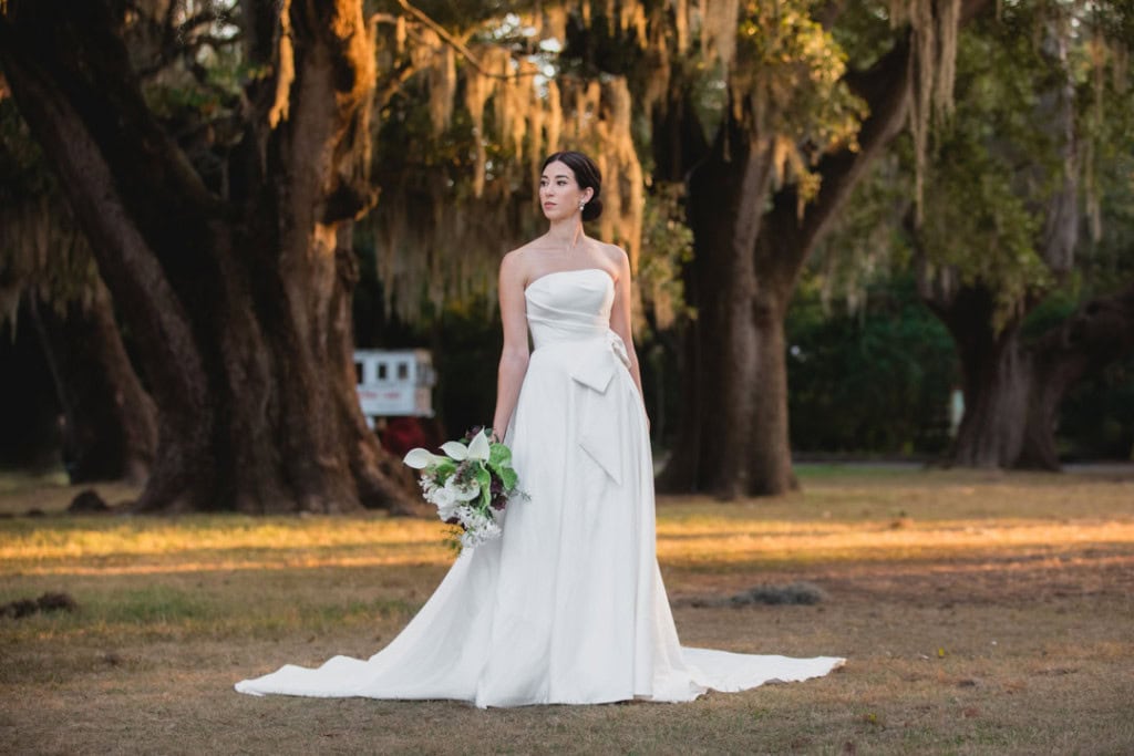 Bride in white wedding dress holding bouquet outdoors at the Audubon Zoo.