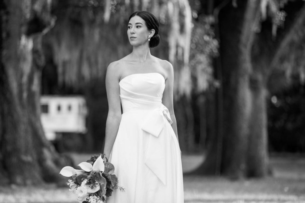 Elegant bride in a white wedding dress holding a bouquet outdoors at the Audubon Zoo in New Orleans.