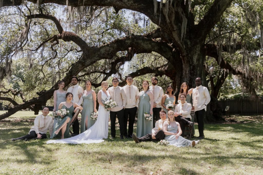 Wedding party under large oak tree in New Orleans with bride and groom.