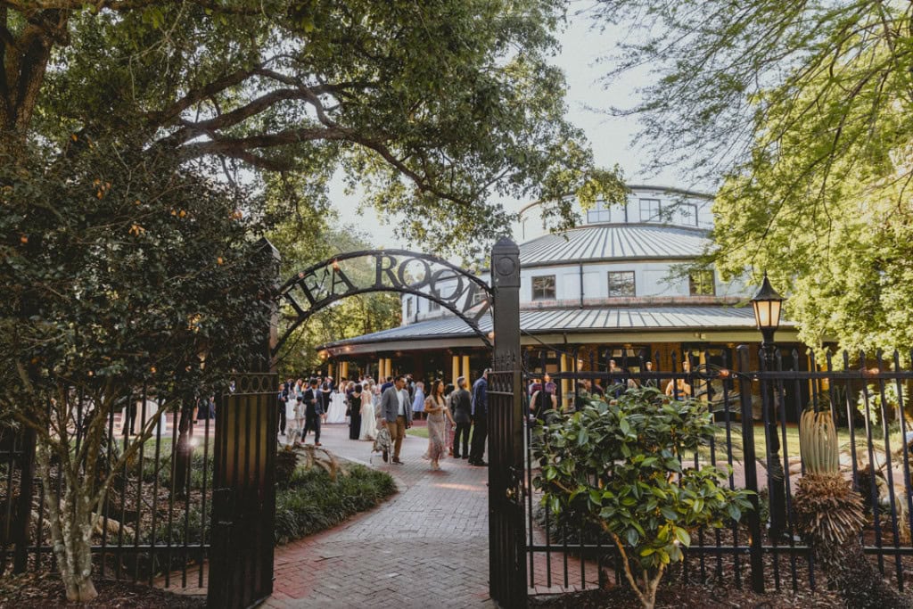 Guests arriving at a the Audubon Tea Room in New Orleans wedding venue with lush trees and historic architecture.